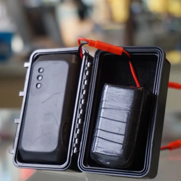 Open case showing the device and a connected battery pack.