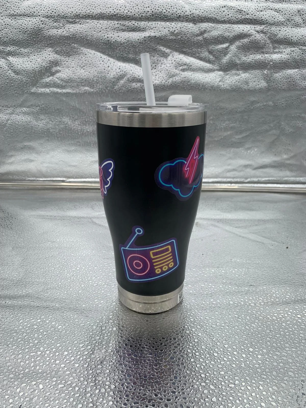 Vaso negro con tapa y pajilla que incorpora una cámara pequeña de audio y video.