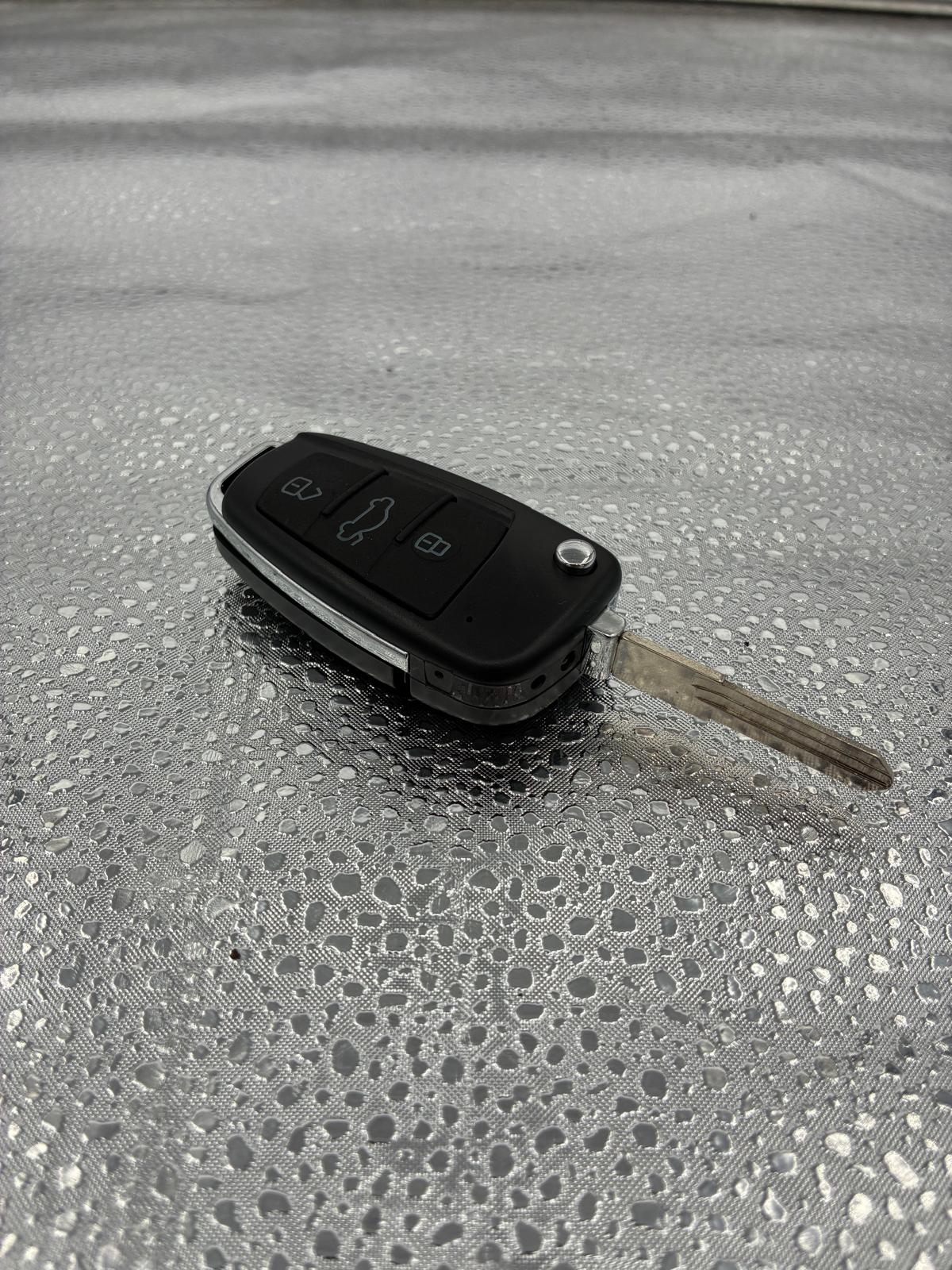 Llave tipo llavero negra sobre fondo plateado