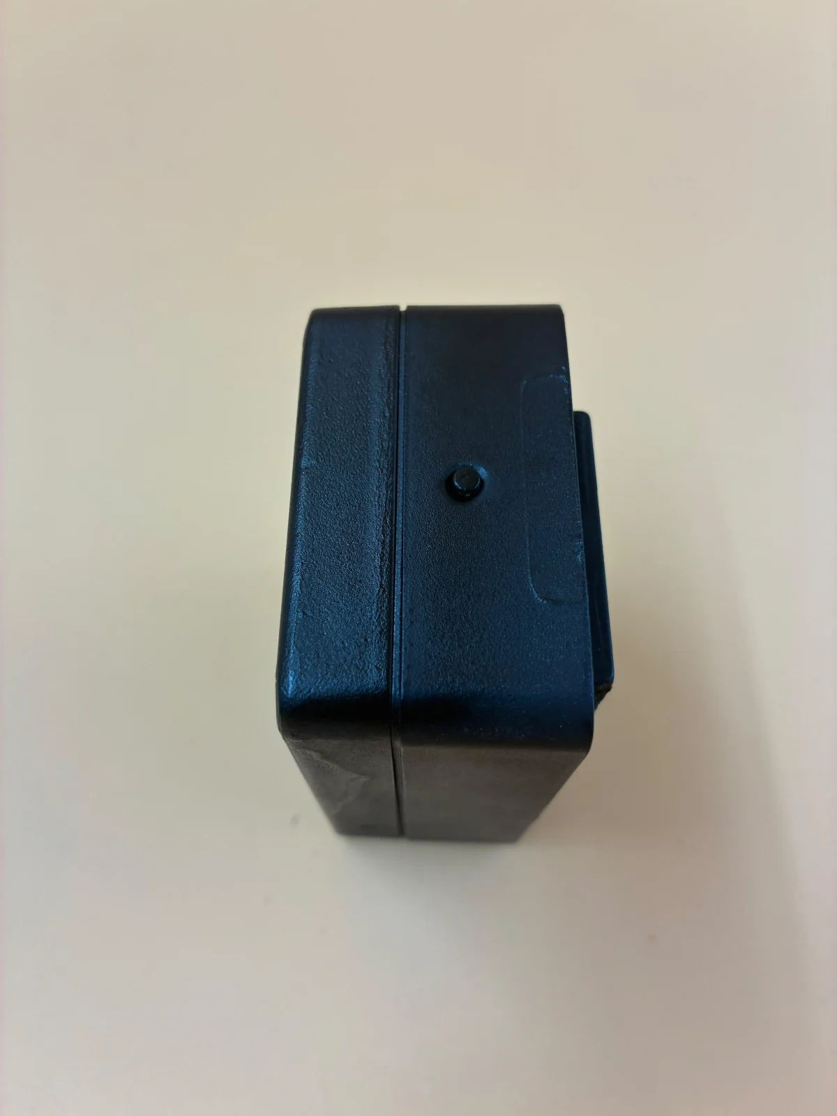 Close-up of a black equipment housing with a small round detail on its side.
