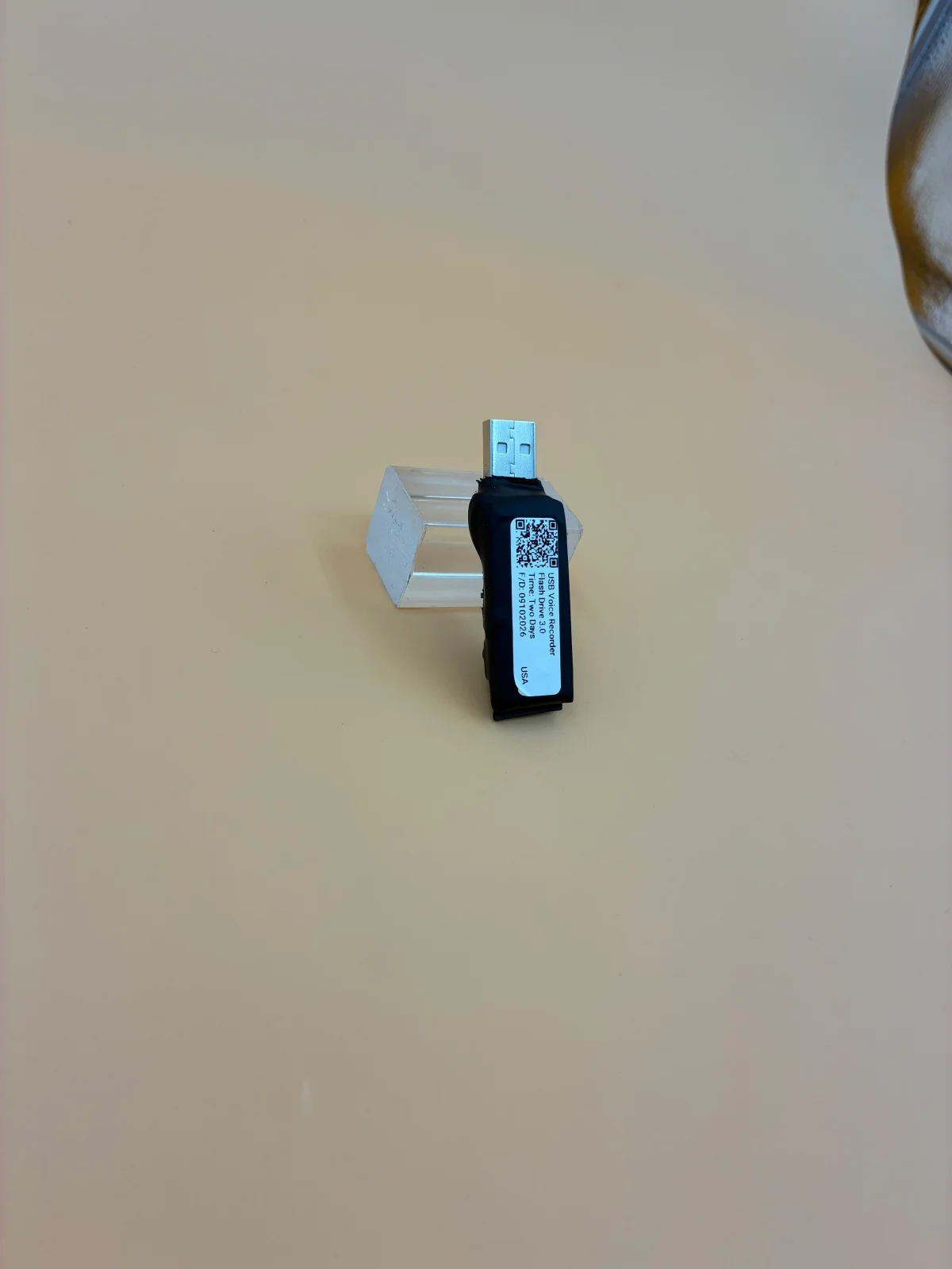 A compact black unit on a clear stand, with its label and USB connector visible.