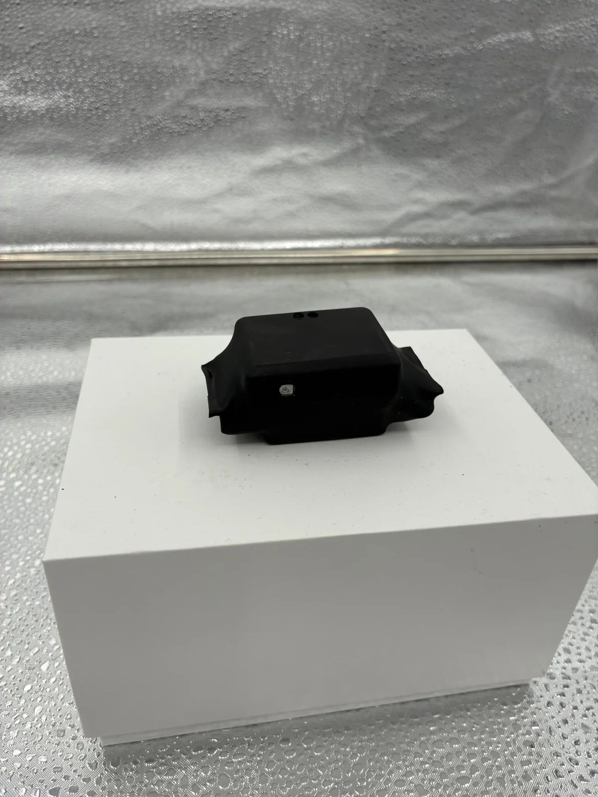 Black equipment housing displayed on a white box, with a button visible on the front.