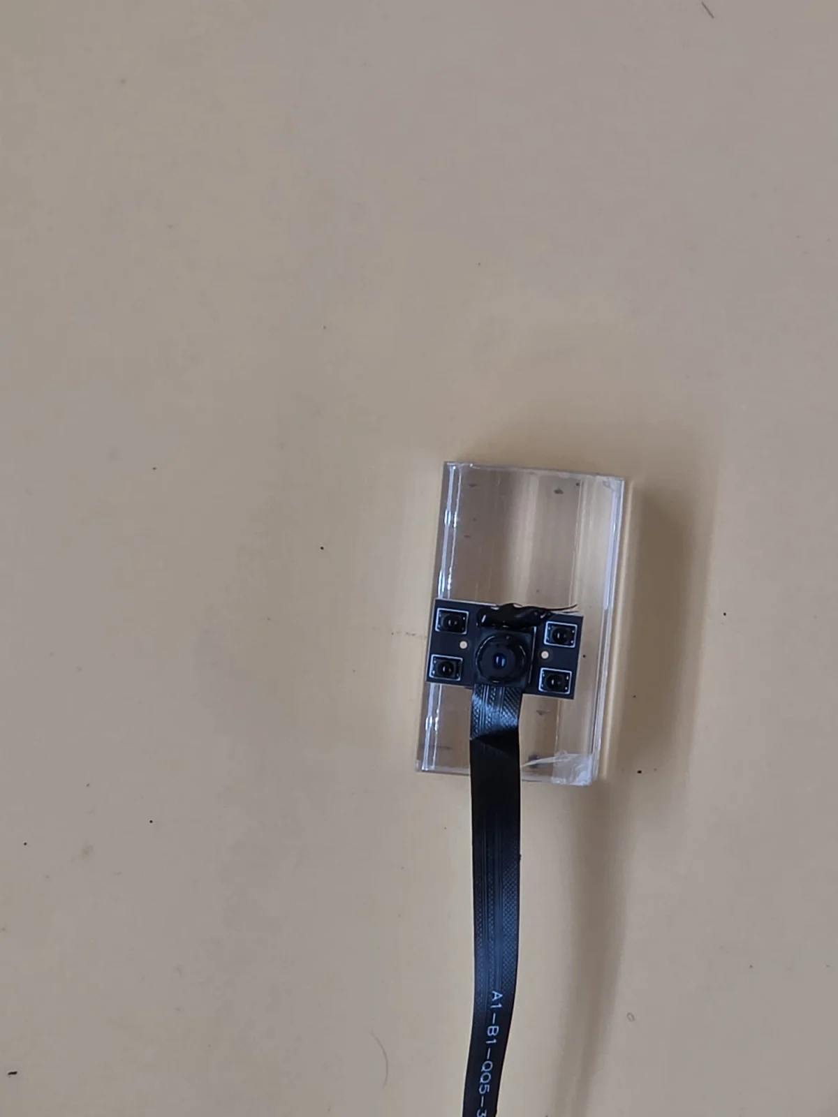 Wider view of the module and its flat cable on a clear display support.