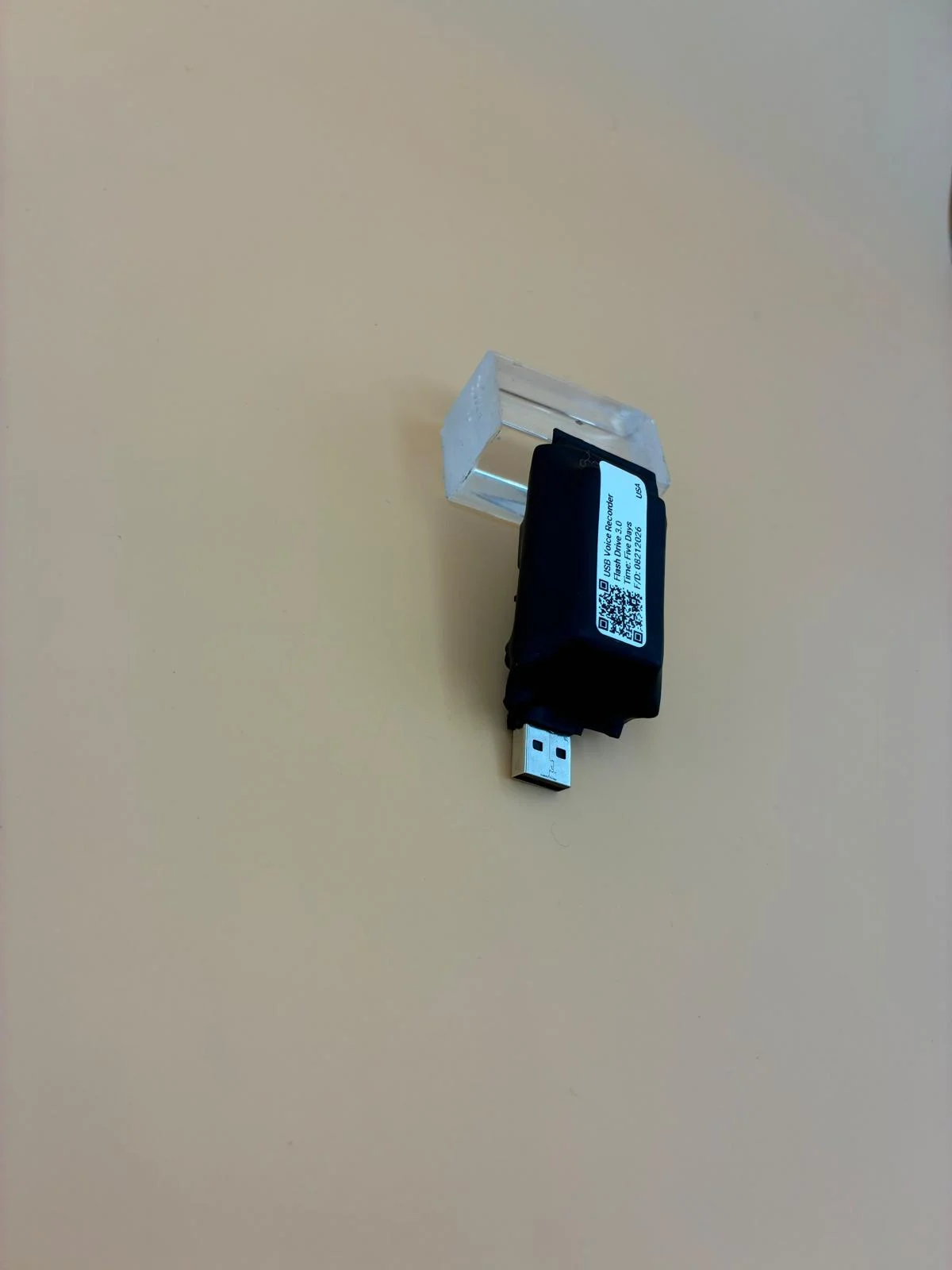 A compact labeled unit resting at an angle on a clear display support.