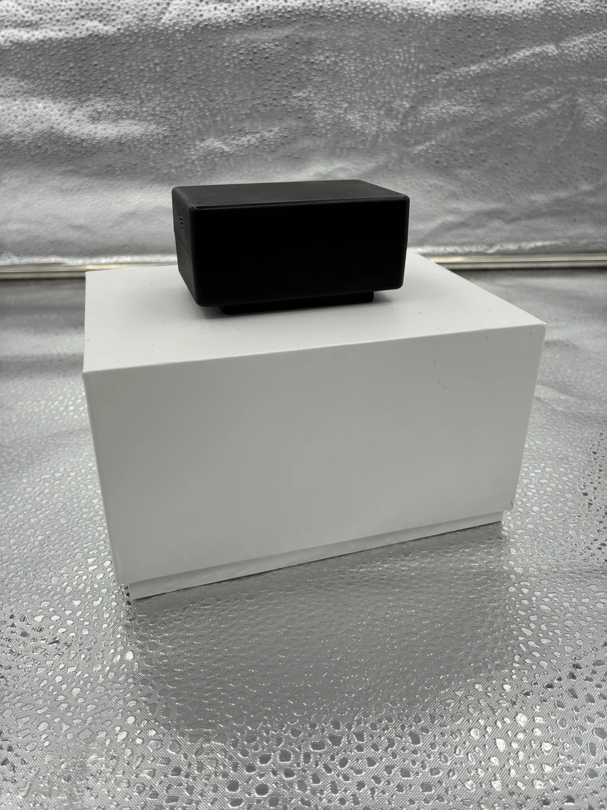 Equipo de carcasa negra y forma rectangular, colocado sobre una caja blanca.