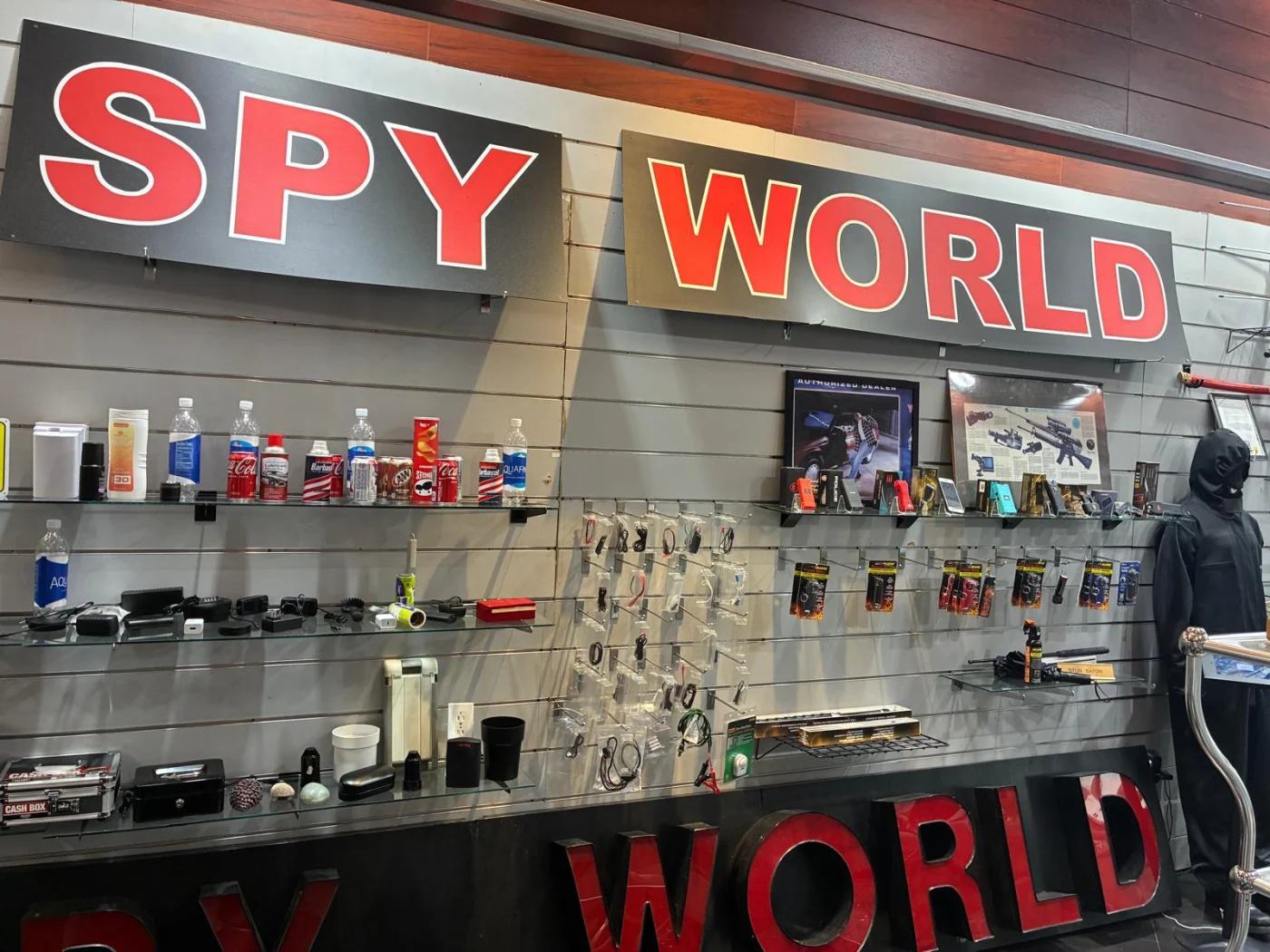 Shelves of devices and accessories beneath the large SPY WORLD signs inside the store.