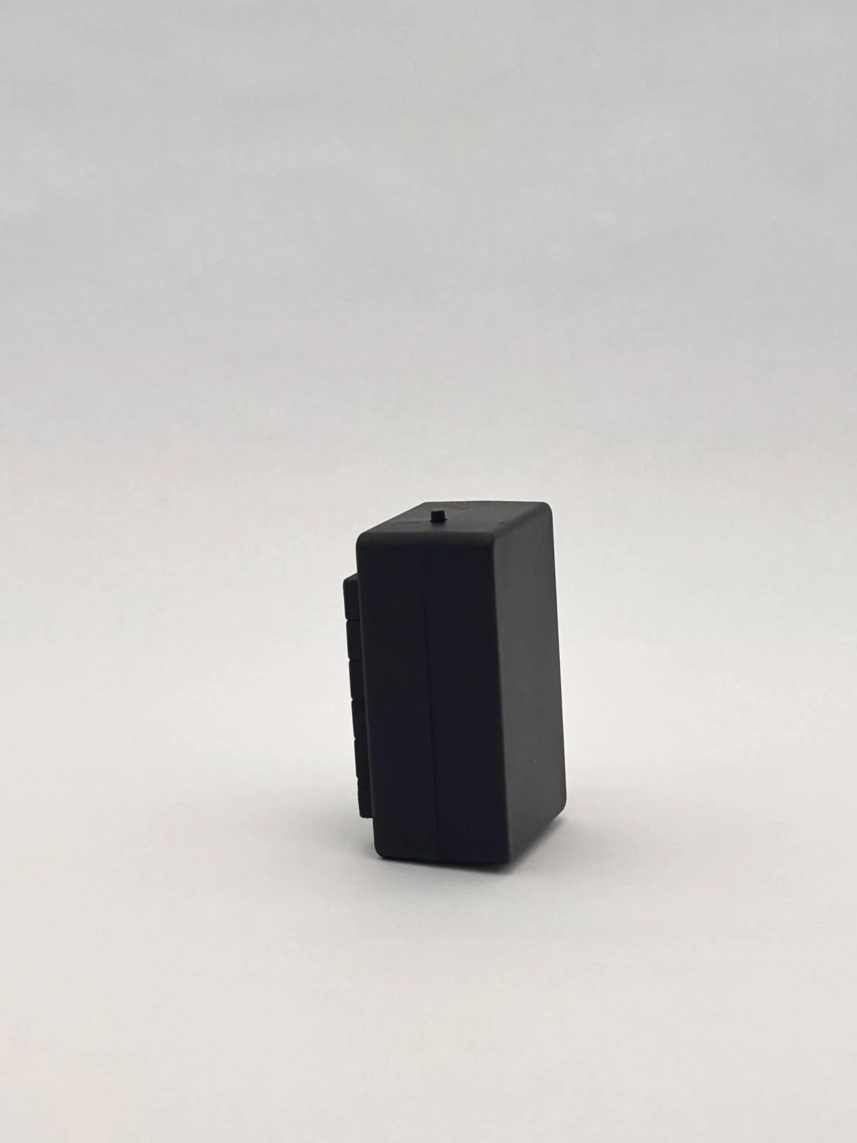 Side view of the black unit standing upright, with a small raised detail on top.