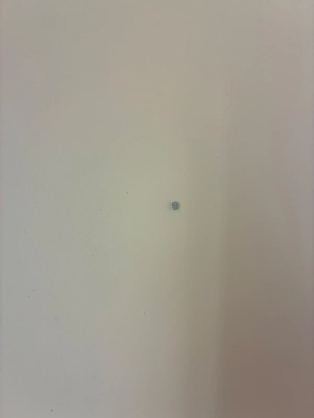 A small circular component photographed on a plain surface.