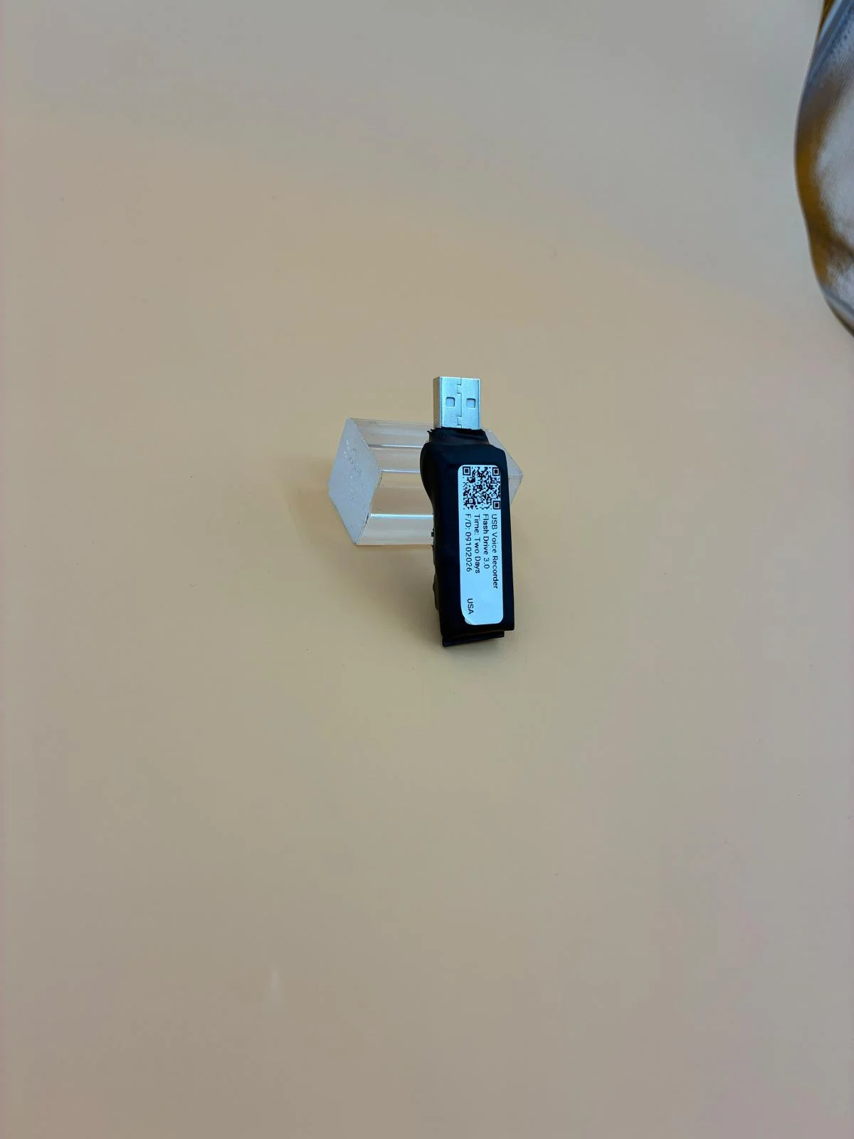 A labeled compact recorder standing against a clear support.